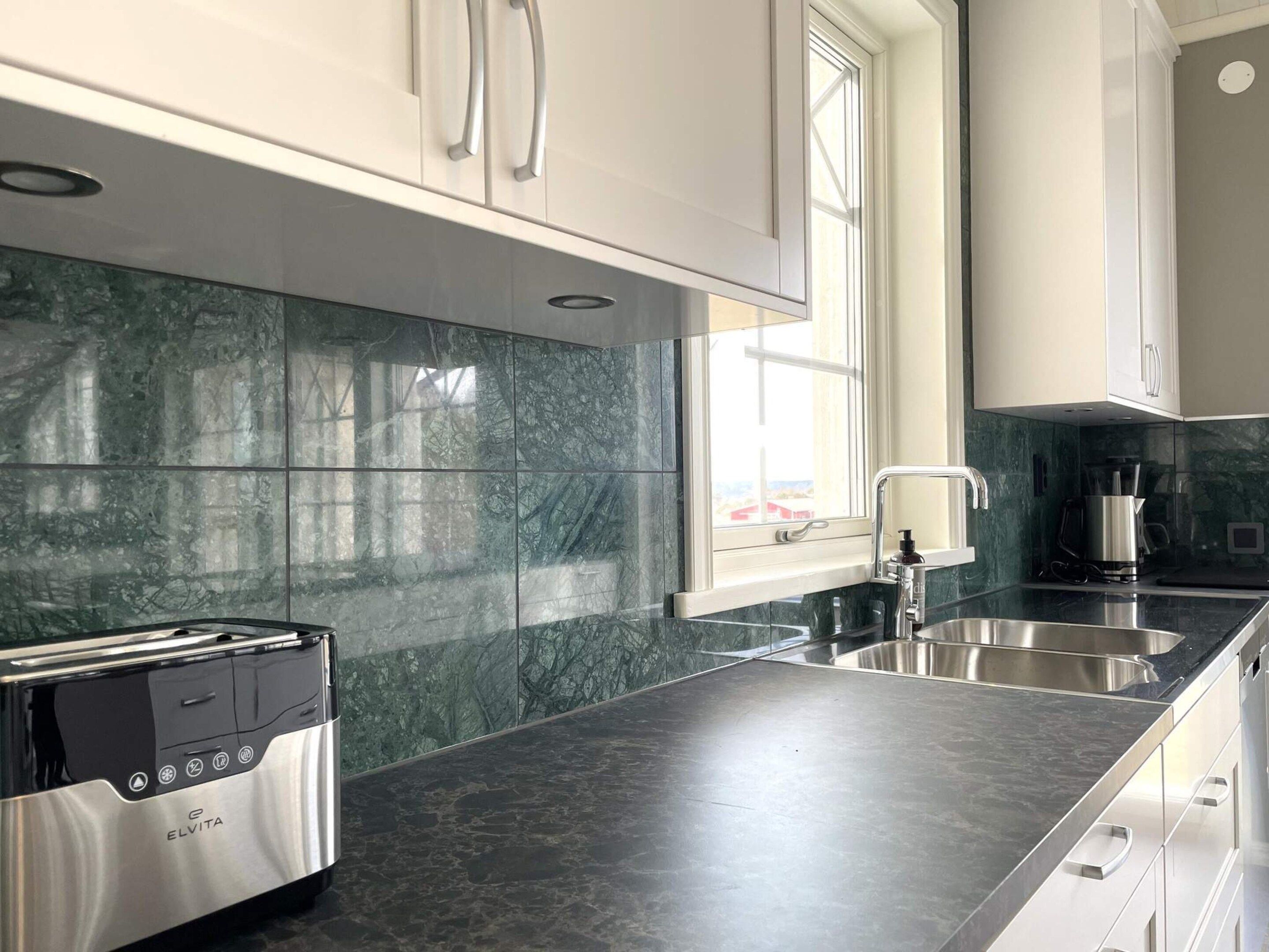 A modern kitchen with a built-in toaster, stainless steel appliances, and a window providing natural light.