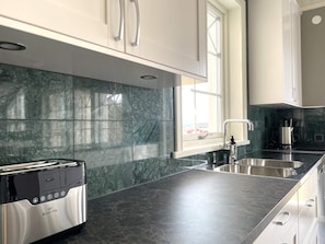 A modern kitchen with a built-in toaster, stainless steel appliances, and a window providing natural light. - 5 Star Holiday Home in Uddevalla (Uddevalla)