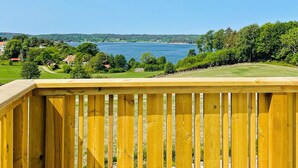 Una terraza de madera con vistas a un lago bajo un cielo despejado.