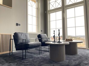 A modern room with two leather chairs, a round table, and large windows offering a view.
