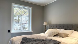 A bedroom with a large window, a bed with multiple pillows, a bedside lamp, and a dark throw blanket. - 5 Star Holiday Home in Uddevalla (Uddevalla)