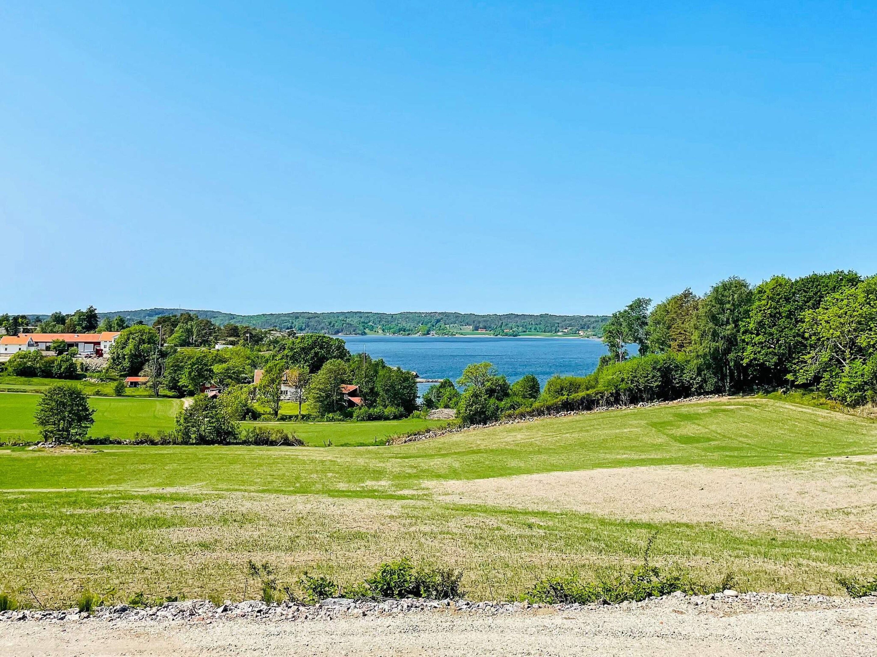 Een kustlandschap met helder uitzicht op de zee, een grasveld en enkele gebouwen in de verte.
