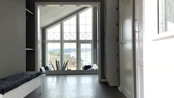 A hallway with a bench, a large window with a view, and a door.