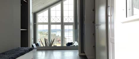 A hallway with a bench, a large window with a view, and a door.