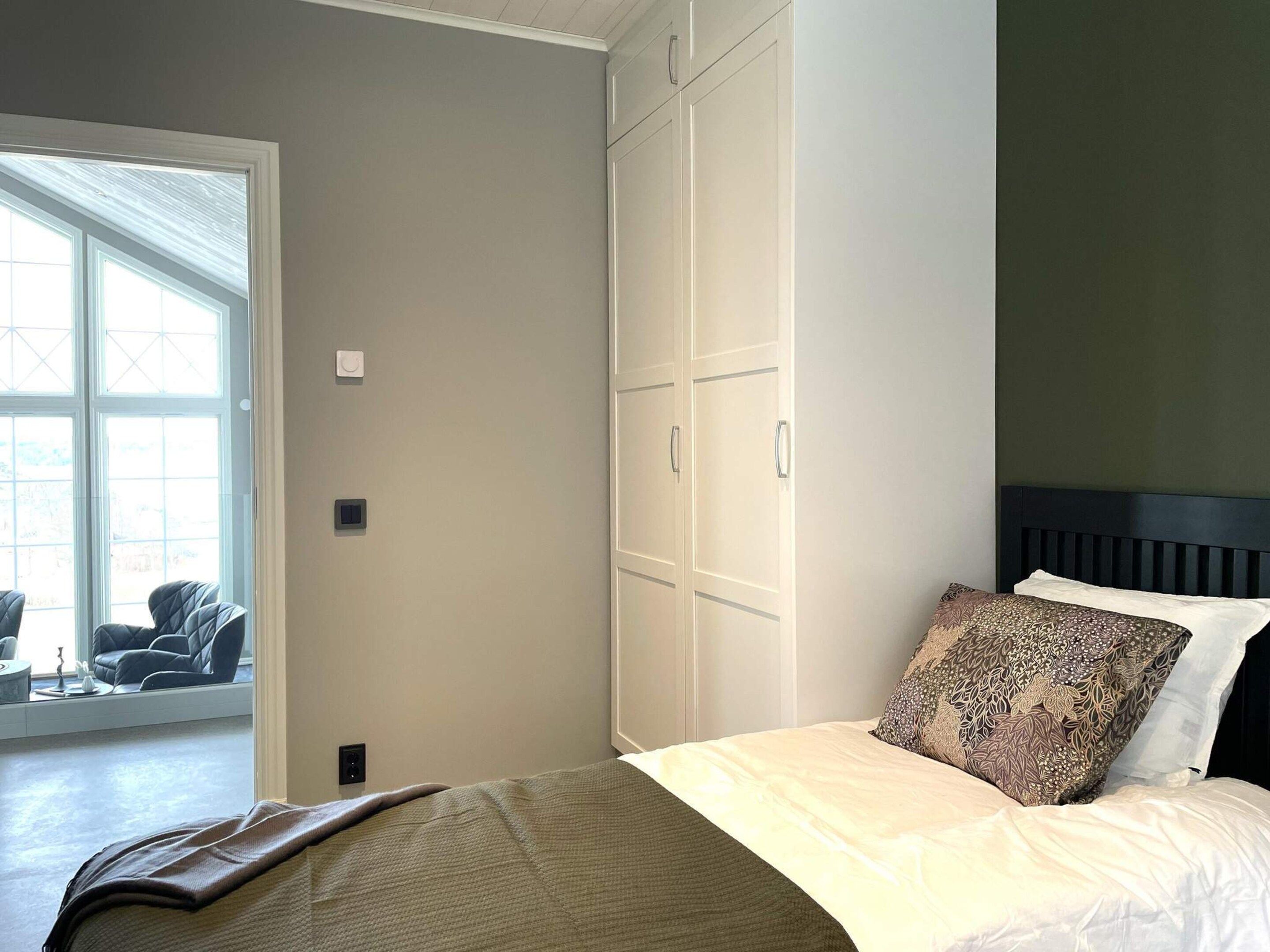 Een slaapkamer met een bed, een kledingkast en uitzicht op een terras.