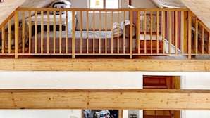 Een slaapkamer op een loft met een houten leuning, een raam en uitzicht op de verdieping beneden.
