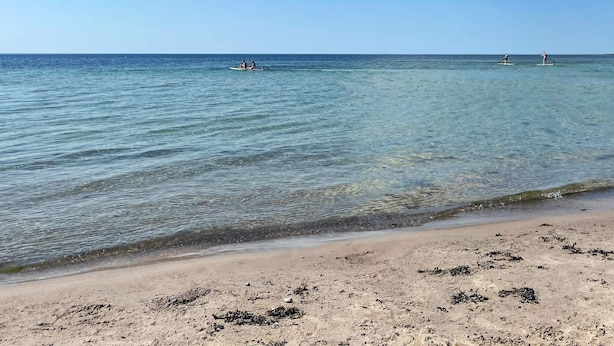 Een strand met helder water en een zandkust.
