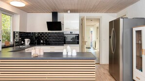 Eine moderne Küche mit Schwarz-Weiß-Farbgebung, einem eingebauten Backofen und einem großen Kühlschrank.