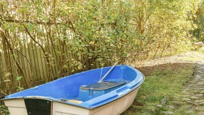 Ein kleines, blau-weißes Boot mit einem Paddel, abseits eines Steinwegs auf einer Rasenfläche geparkt.