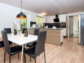 Ett modernt kök med en köksö i mitten, svarta stolar och ett matbord med en vas med blommor.