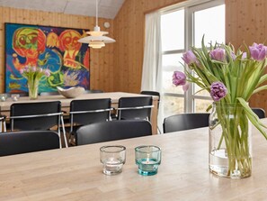A dining area with a wooden table, chairs, a vase of purple tulips, and a candle in a glass holder. - 22 Person Holiday Home in Blavand (Blavand)