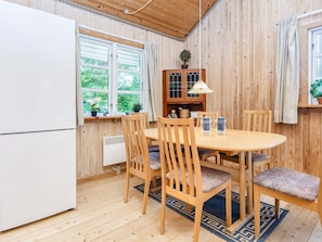 A wooden-paneled room with a round table, chairs, a white refrigerator, and a cabinet with a lamp. - 6 Person Holiday Home in Glesborg (Glesborg)