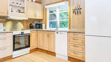 A kitchen with wooden cabinets, a microwave, an oven, and a refrigerator.