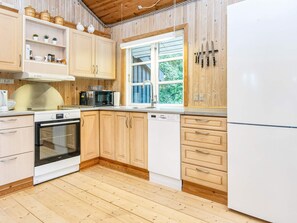 Ett kök med träskåp, en mikrovågsugn, en ugn och ett kylskåp.