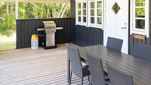 An outdoor patio with a grill, wicker chairs, and a table. - 6 Person Holiday Home in Glesborg (Glesborg)