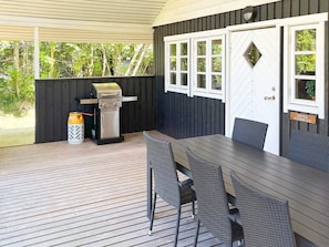 An outdoor patio with a grill, wicker chairs, and a table.