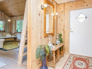 A wooden interior with a sofa, a dining table with candles, and a mirror. - 6 Person Holiday Home in Glesborg (Glesborg)