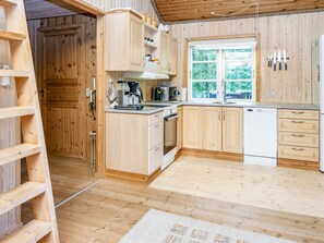 A compact kitchen with wooden cabinets, a coffee maker, a microwave, and a dishwasher. - 6 Person Holiday Home in Glesborg (Glesborg)