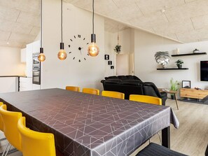 A modern dining area with a geometric-patterned table, yellow chairs, and a black sofa. - 10 Person Holiday Home in Idestrup (Idestrup)