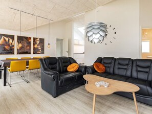 A modern living room with a black leather sofa, yellow chairs, and a wooden coffee table. - 10 Person Holiday Home in Idestrup (Idestrup)