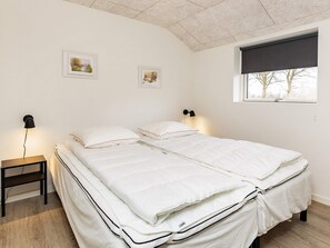 A bedroom with a bed, bedside tables, wall-mounted lamps, and a window with a view. - 10 Person Holiday Home in Idestrup (Idestrup)
