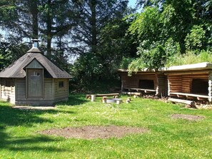 A rustic cabin with a small porch and a chimney, surrounded by a grassy area with trees. - 8 Person Holiday Home in Henne (Henne)