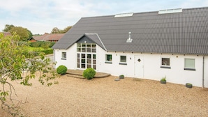 A single-story building with a sloped roof, a large front window, and a gravel driveway. - 8 Person Holiday Home in Henne (Henne)