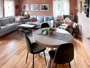 A cozy living room with a grey sofa, a round dining table with chairs, and a wooden floor. - 4 Person Holiday Home in Finnas-by Traum (Bomlo)
