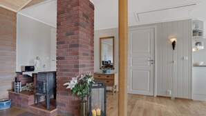 Ein Zimmer mit Kamin aus Backsteinen, Holzboden, weißer Tür und einem Spiegel an der Wand.
