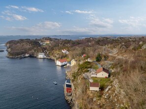 A coastal village with houses on rocky terrain, a small dock, and a clear view of the sea. - 4 Person Holiday Home in Finnas-by Traum (Bomlo)