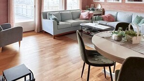 Ein gemütliches Wohnzimmer mit einem grauen Sofa, einem Esstisch mit Stühlen und einem Couchtisch.