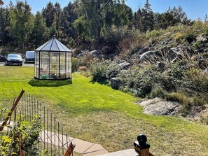 A gazebo in a grassy area with a fence and trees in the background. - 4 Person Holiday Home in Huddinge (Huddinge)