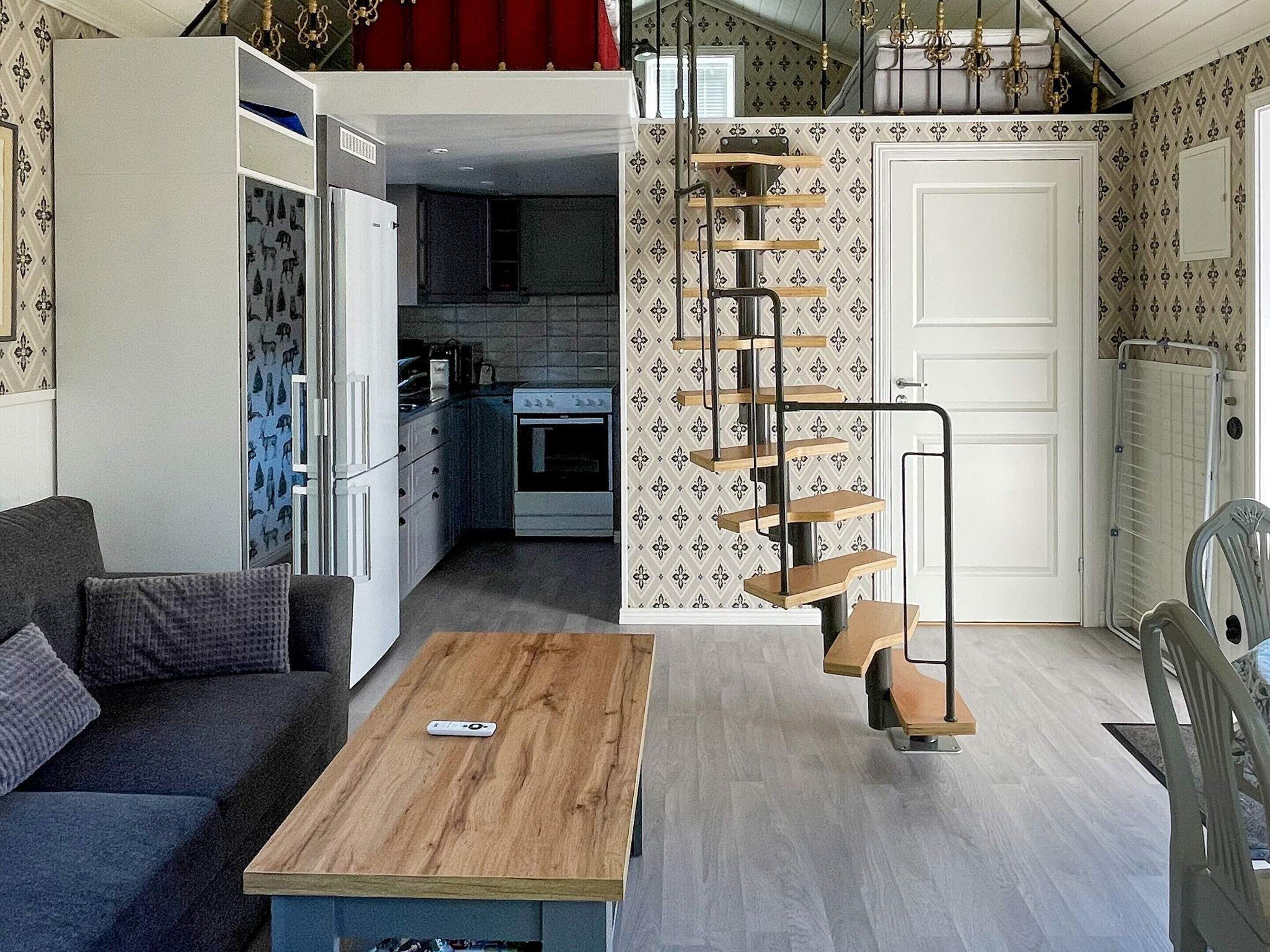 A compact living space with a kitchenette, a sofa, a coffee table, and a spiral staircase.