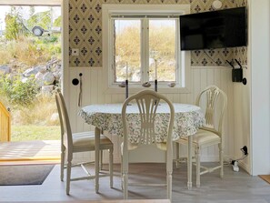 Un coin repas avec une table et des chaises, une fenêtre donnant sur l’extérieur et un téléviseur à écran plat fixé au mur.