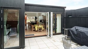 A modern house with a patio area, a dining table, and a covered outdoor seating area. - 5 Star Holiday Home in Gilleleje (Gilleleje)