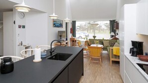 A modern kitchen with a black countertop, white cabinets, and pendant lighting. - 5 Star Holiday Home in Gilleleje (Gilleleje)