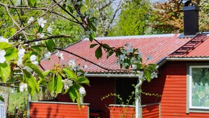 A red wooden house with a porch, two red chairs, and a blooming tree. - 4 Person Holiday Home in Axvall-by Traum (Axvall)