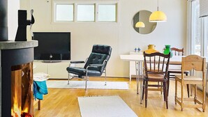 A living room with a fireplace, a TV, a black leather chair, wooden dining table, and chairs. - 4 Person Holiday Home in Axvall-by Traum (Axvall)