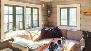 Ein gemütliches Blockhaus-Interieur mit einer Couch, einem Holztisch und einem Ledersessel.
