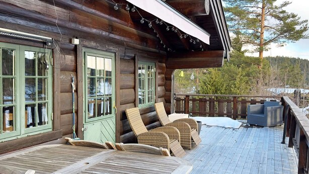 Eine Blockhütte mit einer Terrasse, ausgestattet mit Liegestühlen und einem Tisch.