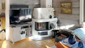 Ein Wohnzimmer mit Fernseher, Kamin und Holzwänden.