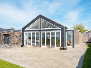 A modern house with a large glass conservatory, a brick garage, and a paved driveway. - 8 Person Holiday Home in Odder (Odder)