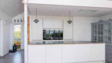 A modern kitchen with a central island, pendant lighting, and a view into the adjacent dining area.