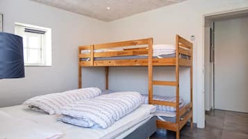 A bunk bed room with a window, a door, and a flat bed with pillows.