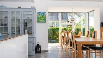 A modern kitchen with a dining area, featuring a large window, a cabinet with glass doors, and a table with chairs.