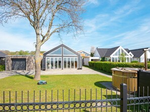 A residential property with a large glass conservatory, a fenced yard, and a well-maintained lawn. - 8 Person Holiday Home in Odder (Odder)