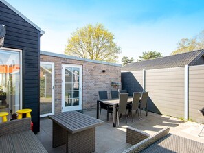 An outdoor patio area with a table and chairs, a small seating area, and a door leading to a covered space. - 8 Person Holiday Home in Odder (Odder)