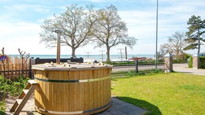 En träkonstruktion formad som en tunna, placerad i en park med utsikt över havet och träd.