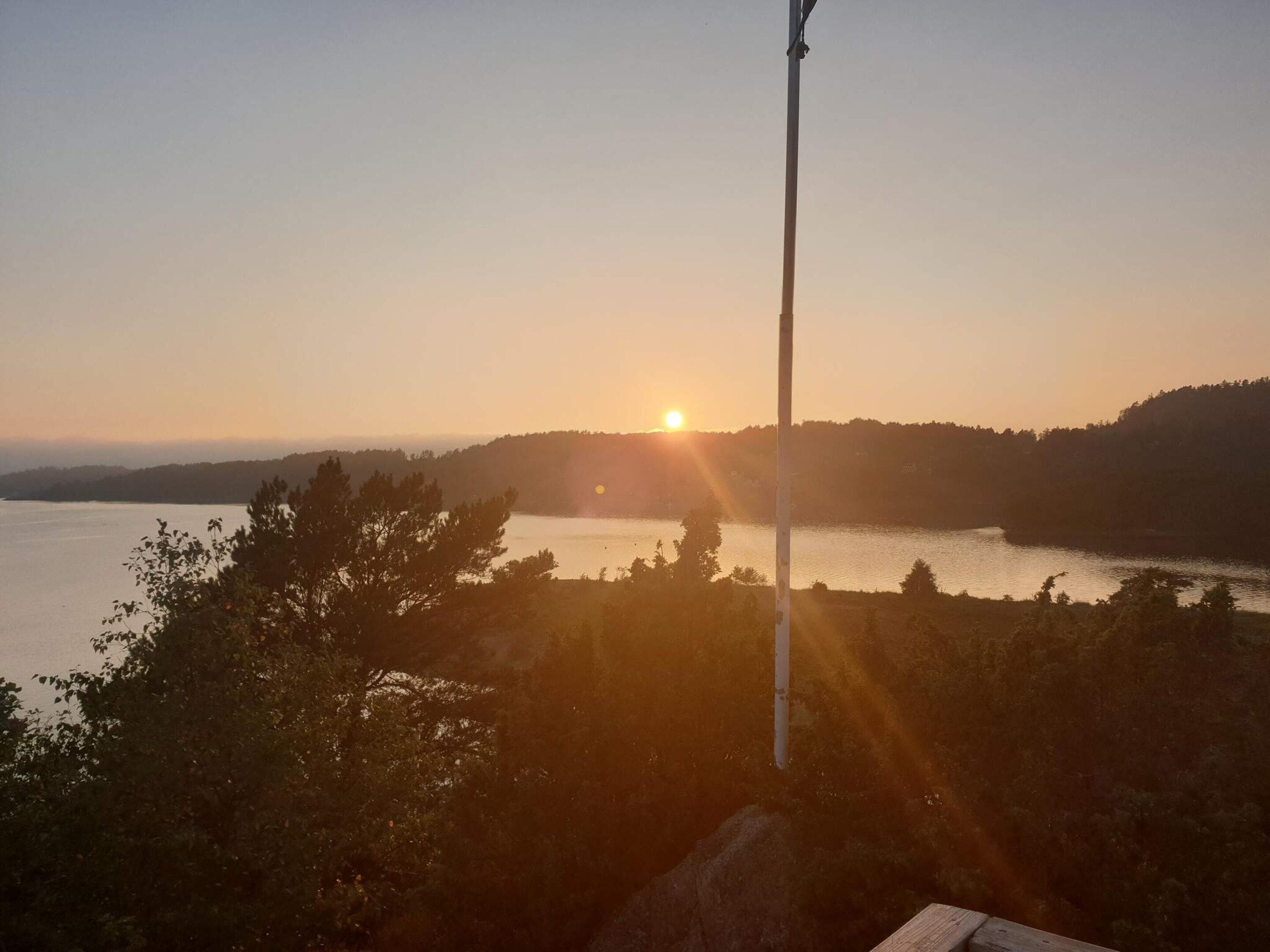A sunset over a lake with a forested hill in the background.