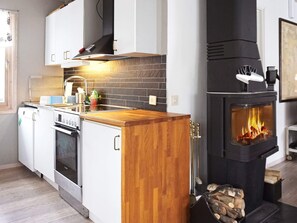 Una cocina moderna con estufa de leña, armarios blancos y una isla de madera.